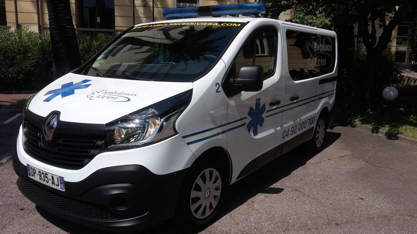 Ambulance Renault Trafic blanche aux couleurs des Ambulances Riviera, portant le numéro 04 92 000 700, stationnée à Nice